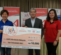 Penyerahan 'mock up cheque' daripada En Keiji Kaneko (tengah) bersama Pn. Lau Chin Mun (kanan) kepada Pengarah Eksekutif HOPE Worldwide Malaysia, Cik Katy Lee (kiri)